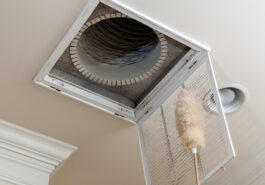 Dusting the vent for air conditioning filter in ceiling of modern home