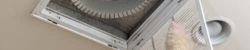 Dusting the vent for air conditioning filter in ceiling of modern home